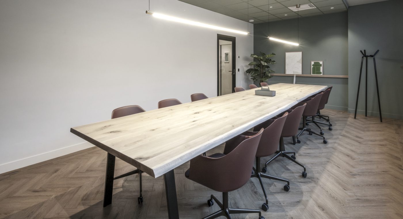 Salle de réunion avec grande table en bois massif et fauteuils de bureau