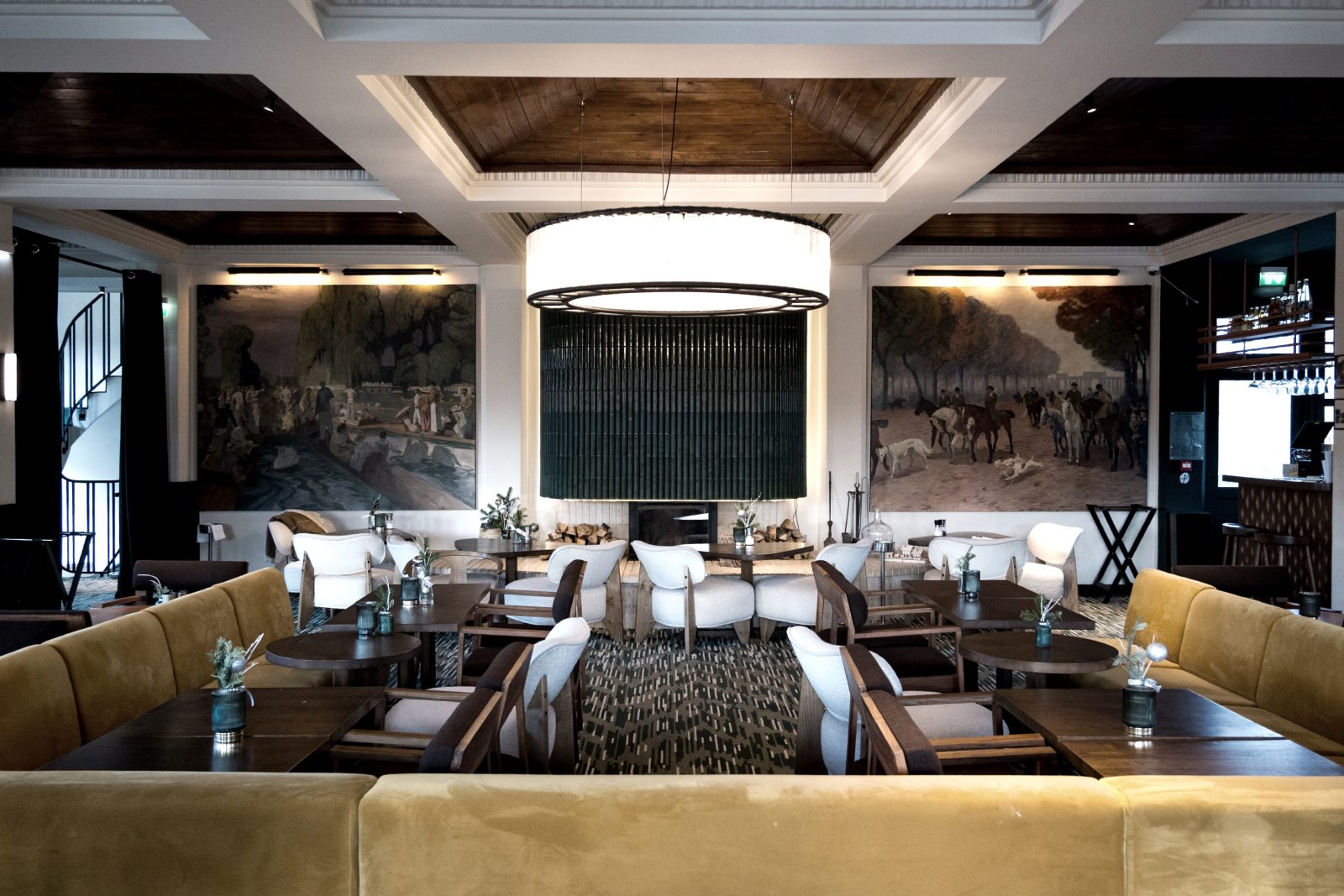 Salle de restaurant avec banquettes en velours, fauteuils et grand lustre rond