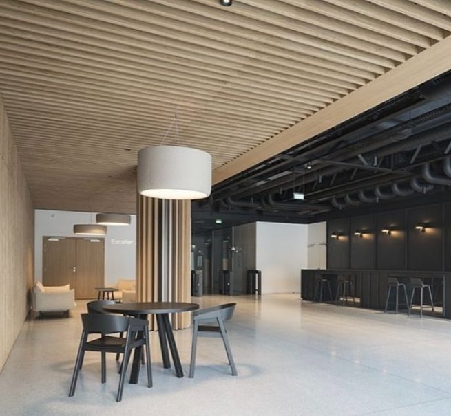 Hall avec table ronde, chaises noires et plafond en lames de bois