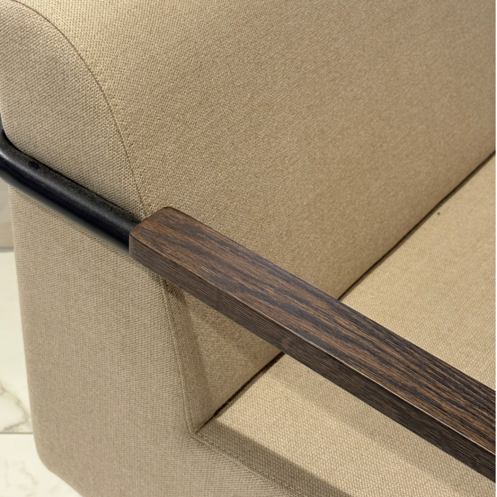 Gros plan sur l’accoudoir en bois foncé et le tissu beige du fauteuil Mommo